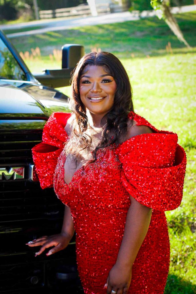 Prom photo in a red dress in front of a Ram truck